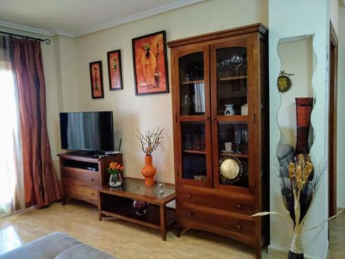 sala de estar con TV y armario de madera en HOME STAR IV con vistas, en Vera
