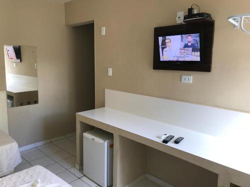 a bathroom with a tv on the wall and a counter at Hotel Coqueiral in Recife