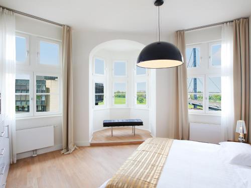 a bedroom with a bed and a bench in front of windows at The Red Apartments in Düsseldorf