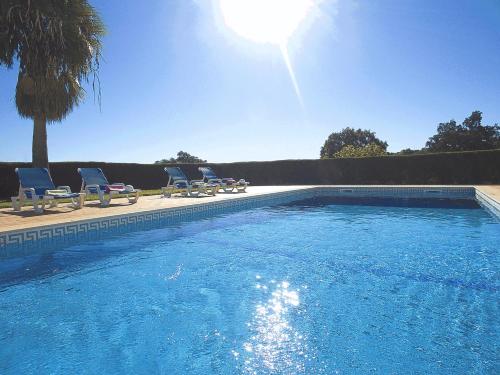 een groot zwembad met stoelen en de zon bij Villa Sardenha by Algarve Vacation in Guia