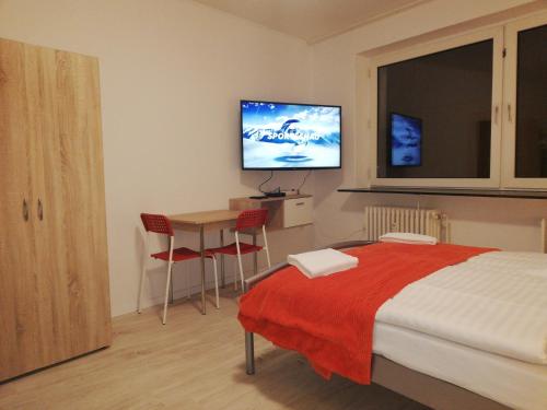 a bedroom with a bed and a table and a flat screen tv at The Hostel in Hamburg