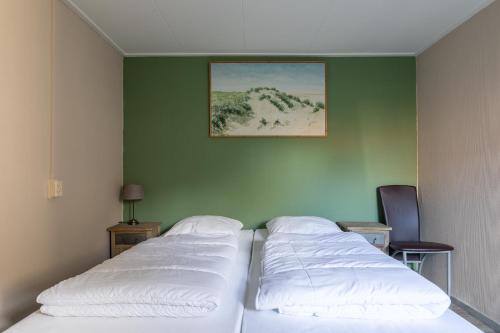 2 Betten in einem Zimmer mit grüner Wand in der Unterkunft T Dûnpantke in Hollum