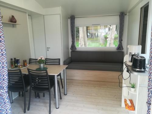 d'une salle à manger avec une table, des chaises et une fenêtre. dans l'établissement MOBIL HOME à QUIBERON 205, à Quiberon