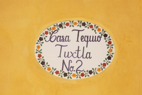 a plate on a yellow wall with the words local tequila tucilla no at Casa Tequio in San Cristóbal de Las Casas