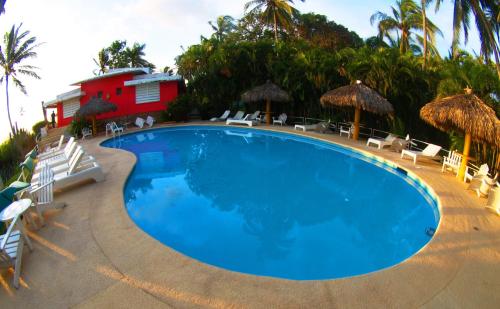 a swimming pool with chairs and a red building at Hotel Flamingos in Acapulco
