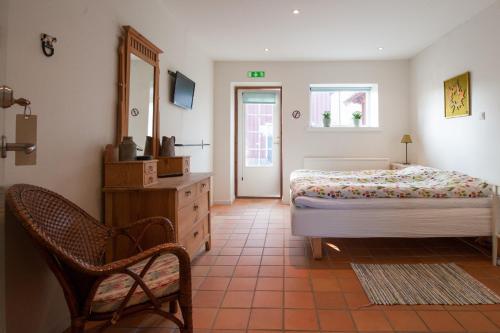 1 dormitorio con cama, silla y espejo en Hunseröds Bed & Breakfast, en Perstorp