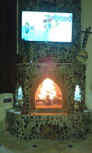 a stone fireplace with a tv on top of it at Villa Paradise in Aghmat