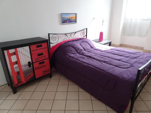 een slaapkamer met een paars bed en een dressoir bij Hébergement Paquebot de Rêve in Saint-Nazaire