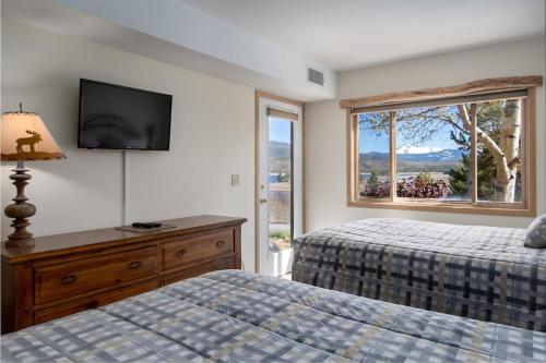 Un dormitorio con dos camas y un televisor y una ventana. en Lake Forest 101B, en Frisco