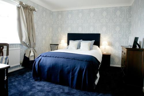 a bedroom with a large bed with blue carpet at Stirk House Hotel in Clitheroe