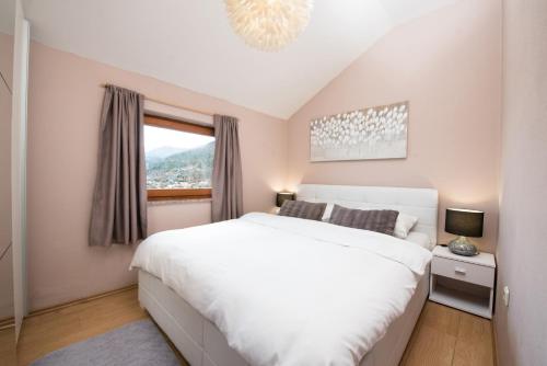 a bedroom with a white bed and a window at Lola Apartment in Veprinac
