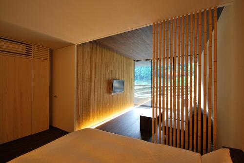a bedroom with a bed and a tv on the wall at Kawayu Onsen Fujiya in Hongu
