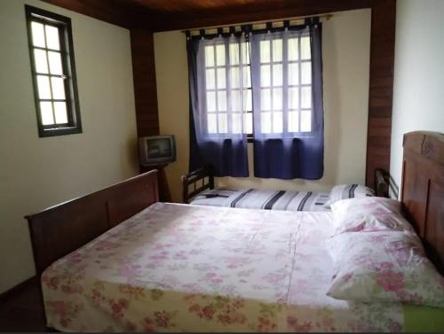 a bedroom with a large bed and two windows at Hospedaria Tinoco in Ipiabas