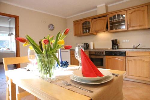 a kitchen with a table with a vase of flowers on it at Ferienwohnung An den Tannen in Bartelshagen