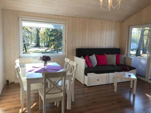 a living room with a couch and a table and chairs at Park Wodny Cieszyno in Połczyn-Zdrój