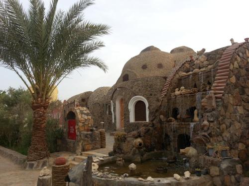 a building with a palm tree next to a fountain at Safari Camp Bahariya Oasis in Bawiti