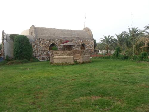 an old stone building with a grass yard at Safari Camp Bahariya Oasis in Bawiti