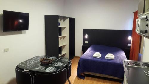 Una habitación con una cama y una mesa en una habitación en Departamento Estudio 2 en Neuquén
