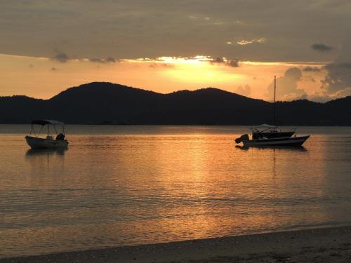 two boats sitting in the water at sunset at Recanto da Praia in Paraty