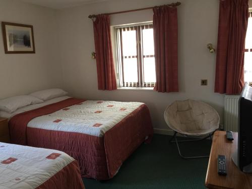 a hotel room with two beds and a television at Parkfield (Chepstow BnB) in Chepstow
