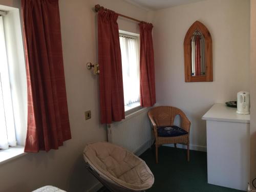 um canto de um quarto com uma cadeira e duas janelas em Parkfield (Chepstow BnB) em Chepstow