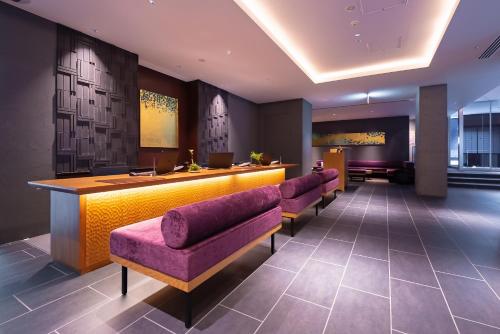 een lobby met een bar met een rij paarse stoelen bij Hotel Vista Premio Kyoto Nagomi tei in Kyoto