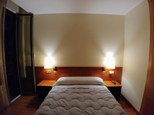 a bedroom with a bed and two lights on the wall at Hostal Prada Borges in León