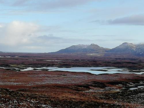 a large body of water in a field with mountains at The Fisherman's Snug self catering North Uist in Paible