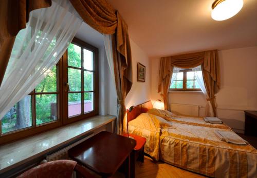 a bedroom with a bed and two windows at Willa Raj in Nałęczów