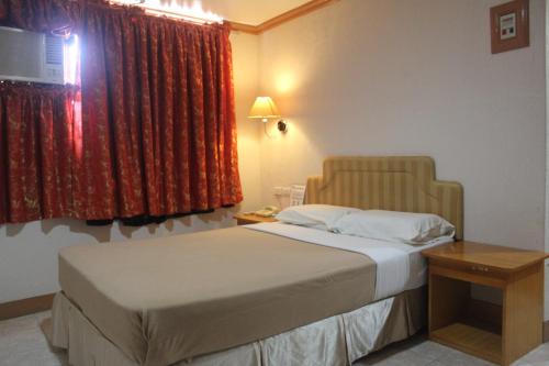 a bedroom with a bed and a window with red curtains at Elegant Circle Inn in Cebu City