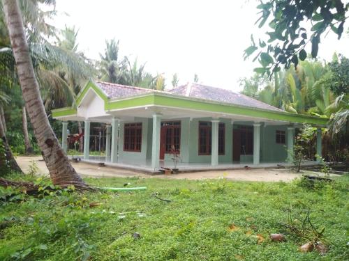 una casa verde y blanca con una palmera en Homestay Buang Sari, en Gresik