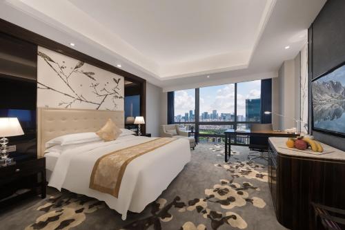 a hotel room with a bed and a desk and a large window at Huaqiang Plaza Hotel Shenzhen, Enjoy Complimentary Afternoon Tea & Mini Bar & Night Snack in Shenzhen