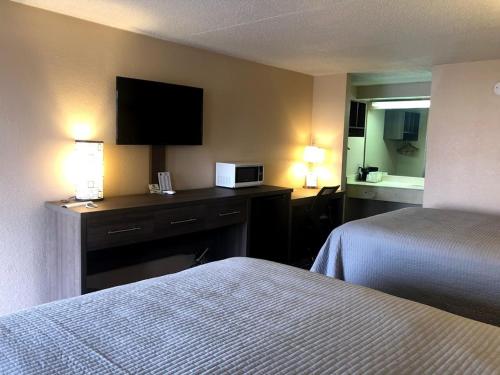 a hotel room with two beds and a television at Legacy Inn - Gallatin in Gallatin