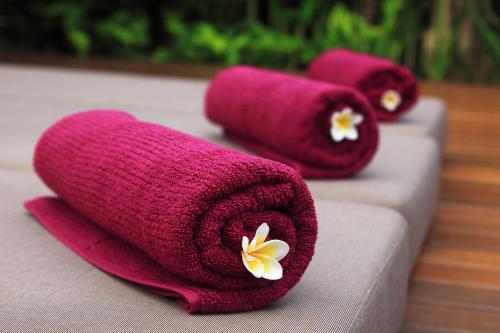 tre asciugamani con fiori sopra seduti su un divano di Villa Jumah a Seminyak