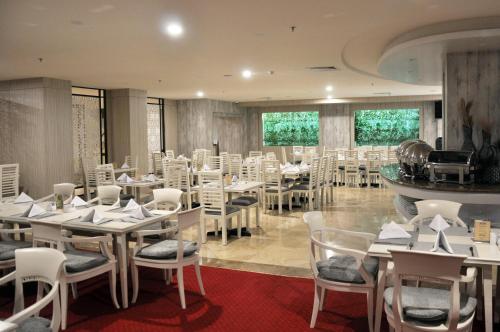 a dining room with white tables and chairs at Beverly Hotel Batam in Nagoya