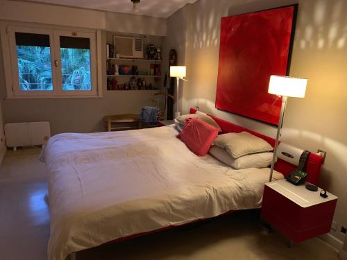 a bedroom with a large bed with a red painting on the wall at Deaf twins bed/breakfast in San Isidro