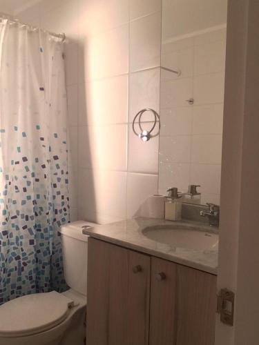 uma casa de banho com um WC, um lavatório e um espelho. em Departamento Familiar Linda Vista Condominio BordeMar Los Molles em Los Molles