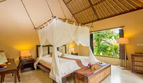 a bedroom with a canopy bed and a window at The Sungu Resort & Spa in Ubud
