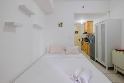 a bedroom with a white bed and a kitchen at Studio Apartment at M-Town Residence near Summarecon Mall Serpong By Travelio in Pumpangsineng