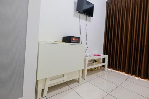 a room with a television and a table with a tv at Studio Apartment at M-Town Residence near Summarecon Mall Serpong By Travelio in Pumpangsineng