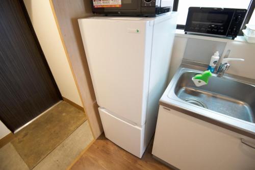 a small kitchen with a white refrigerator next to a sink at Roppongi ClassyHouse902 in Tokyo