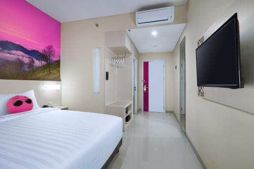 a bedroom with a white bed and a flat screen tv at favehotel Malang in Malang