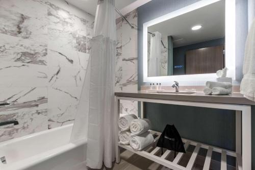 a bathroom with a tub and a sink and a mirror at Cambria Hotel West Orange in West Orange