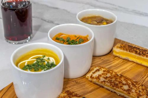 four bowls of soup and bread on a cutting board at Cambria Hotel West Orange in West Orange