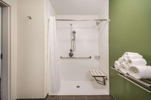 La salle de bains est pourvue d'une douche, de murs verts et de serviettes. dans l'établissement Sleep Inn & Suites Yukon Oklahoma City, à Yukon