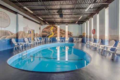 薩德伯里的住宿－薩德伯里克拉麗奧酒店，一个带椅子和绘画的房间的热水浴缸
