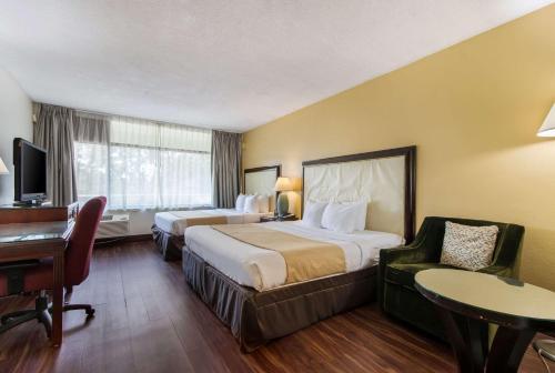 a hotel room with two beds and a desk at Quality Inn Boca Raton University Area in Boca Raton