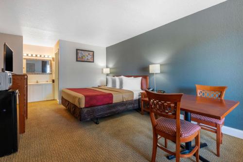 a hotel room with a bed and a desk and a table at Econo Lodge Airport - RJ Stadium in Tampa