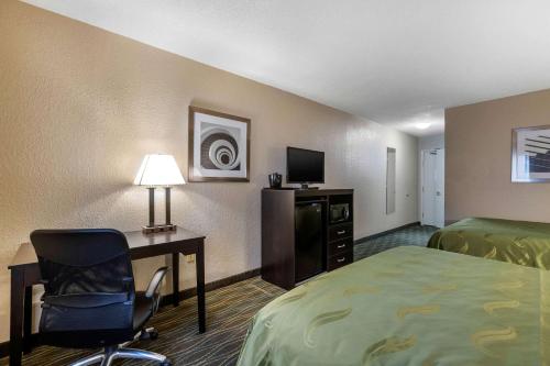 a hotel room with a bed and a desk and a chair at Quality Inn & Suites Des Moines - Merle Hay Road in Urbandale