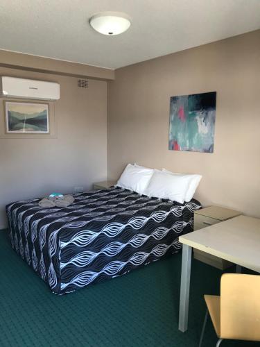 ein Hotelzimmer mit einem Bett und einem Schreibtisch in der Unterkunft Aquatic Motor Inn in Taree